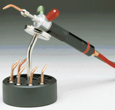 Little torch docked on a magnetic holder base with several copper torch tips stored in the organizer slots.