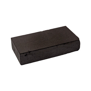 Front angled profile of a rectangular compressed high-density charcoal block tilted left on a white background.