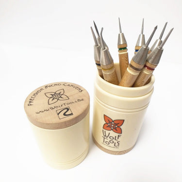 Eight precision micro carvers with wooden handles standing upright in their storage canister.