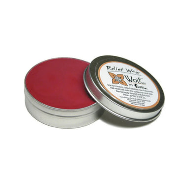Red Wolf Relief Wax in a metal tin with the lid leaning against the side.
